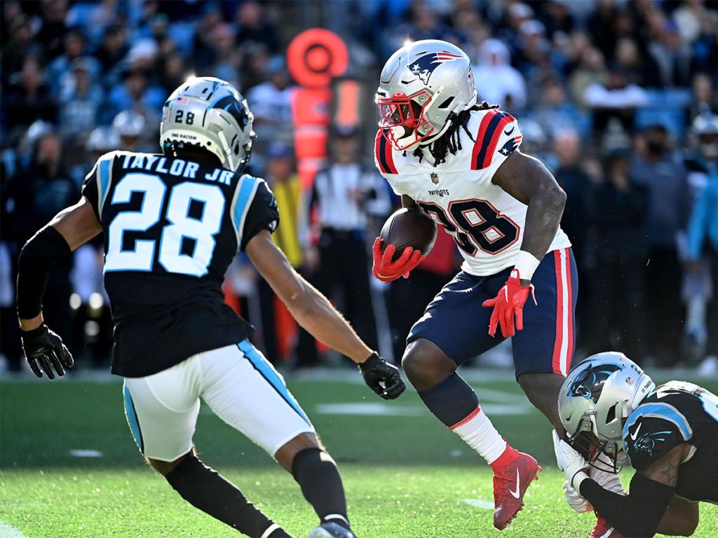 Nov 7, 2021; Charlotte, North Carolina, USA; New England Patriots running back Rhamondre Stevenson (38) with the ball as Carolina Panthers cornerback Keith Taylor (28) and safety Jeremy Chinn (21) defend in the third quarter at Bank of America Stadium. Mandatory Credit: Bob Donnan-USA TODAY Sports