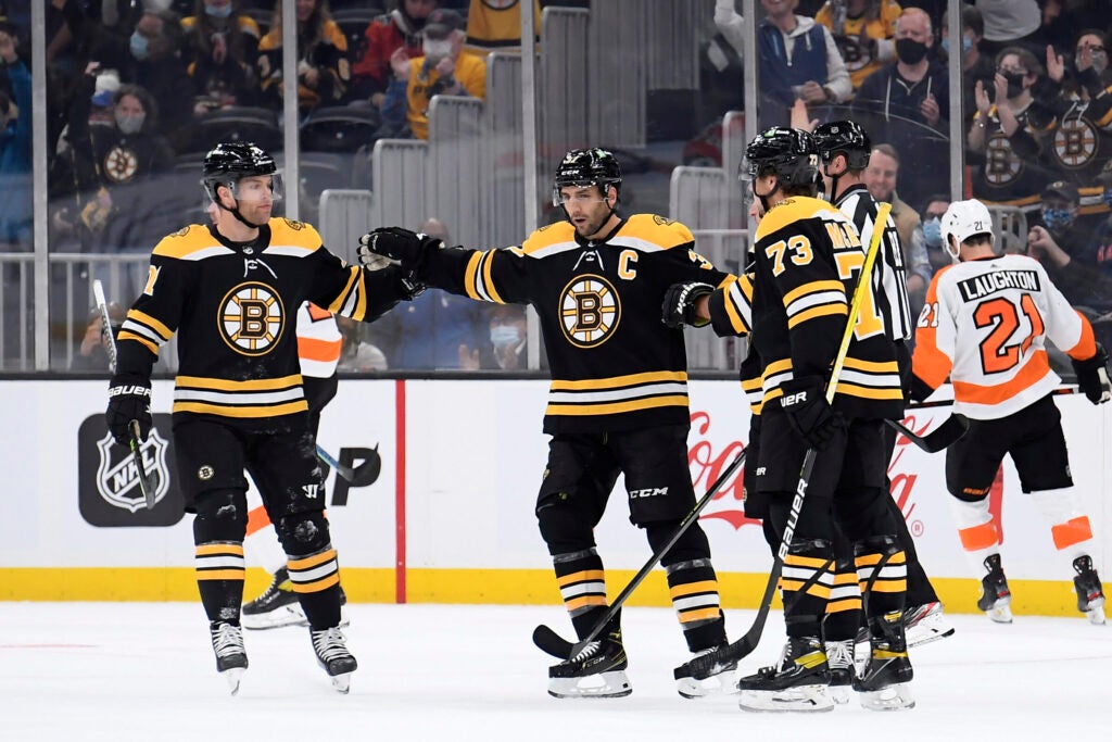 Sep 30, 2021; Boston, Massachusetts, USA; Boston Bruins center Patrice Bergeron (37) celebrates a goal by center Brad Marchand (63) with left wing Taylor Hall (71) and defenseman Charlie McAvoy (73) during the first period against the Philadelphia Flyers at TD Garden. Mandatory Credit: Bob DeChiara-USA TODAY Sports