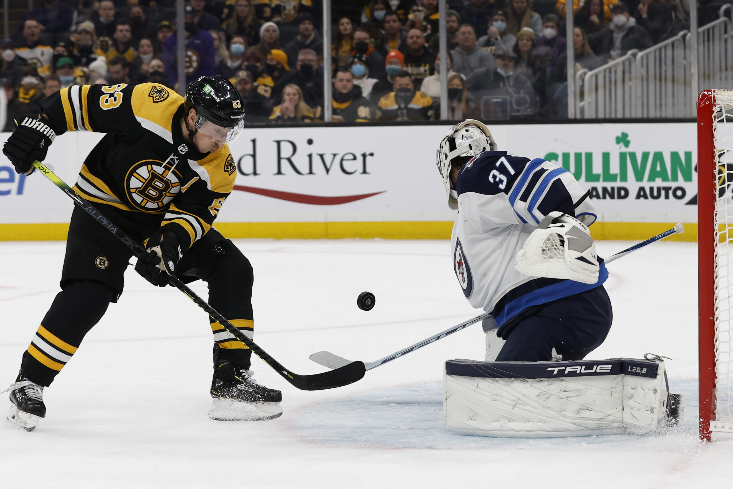Jan 22, 2022; Boston, Massachusetts, USA;Boston Bruins left wing Brad Marchand (63) looks for a rebound in front of Winnipeg Jets goaltender Connor Hellebuyck (37)  during the third period at TD Garden. Mandatory Credit: Winslow Townson-USA TODAY Sports