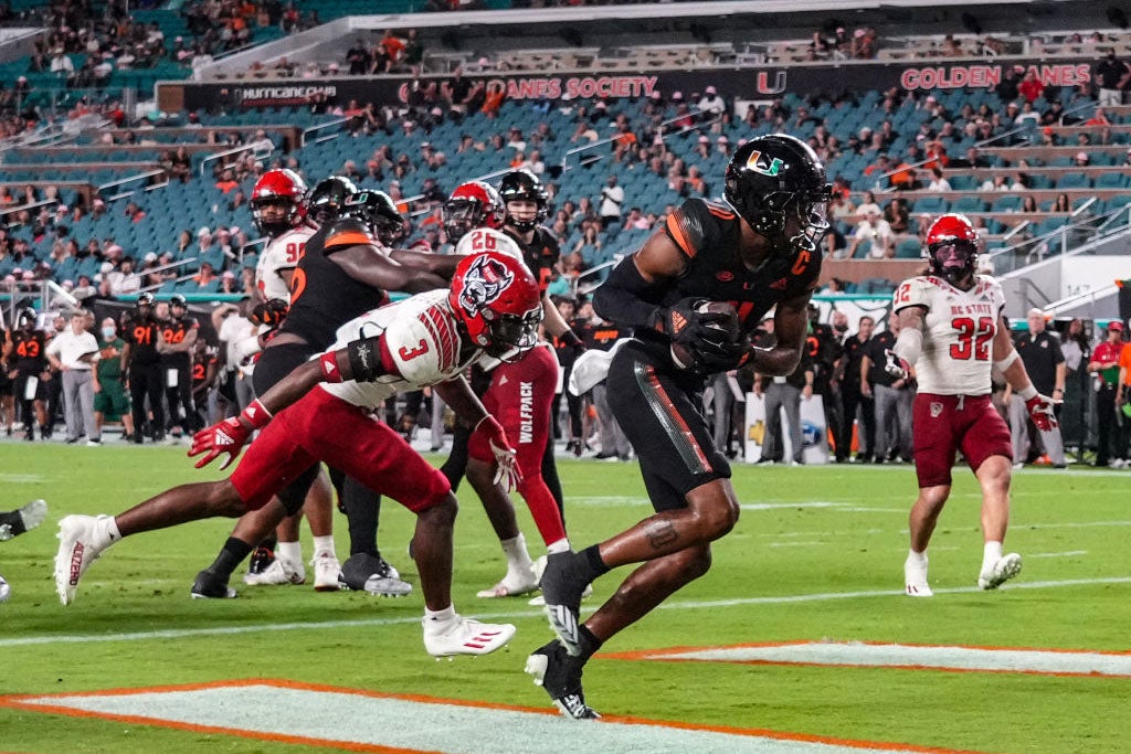 MIAMI GARDENS, FLORIDA - OCTOBER 23: Charleston Rambo #11 of the Miami Hurricanes catches his second touchdown pass against Aydan White #3 of the North Carolina State Wolfpack during the second half at Hard Rock Stadium on October 23, 2021 in Miami Gardens, Florida. (Photo by Mark Brown/Getty Images)