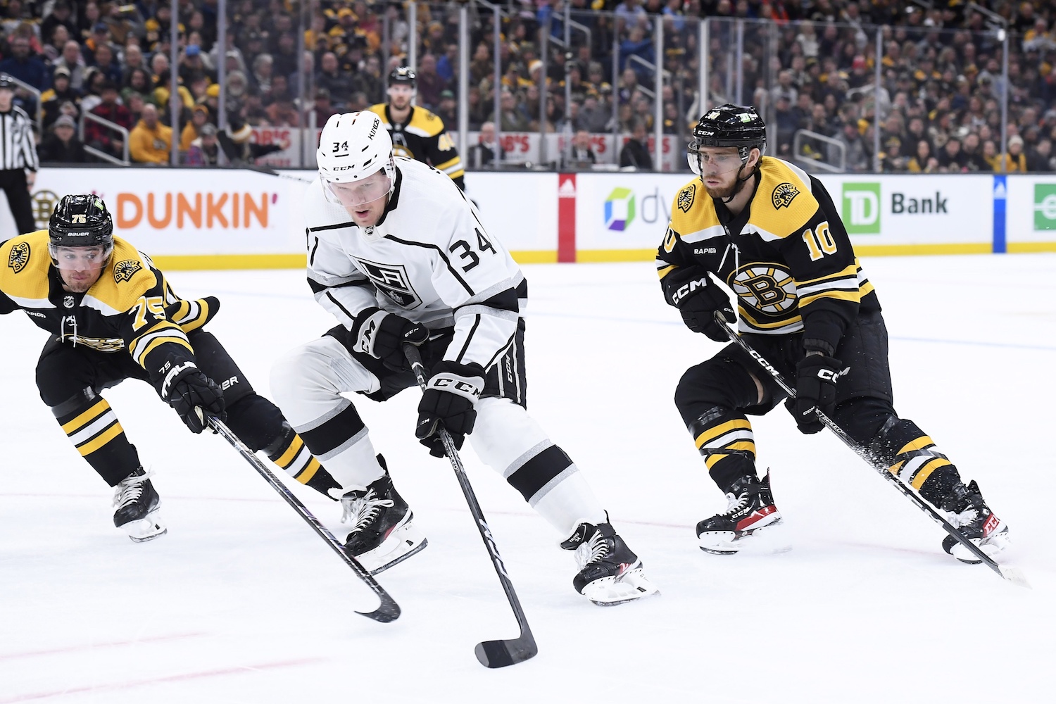 Dec 15, 2022; Boston, Massachusetts, USA;  Los Angeles Kings right wing Arthur Kaliyev (34) controls the puck between Boston Bruins defenseman Connor Clifton (75) and left wing A.J. Greer (10) during the second period at TD Garden. Mandatory Credit: Bob DeChiara/USA TODAY Sports