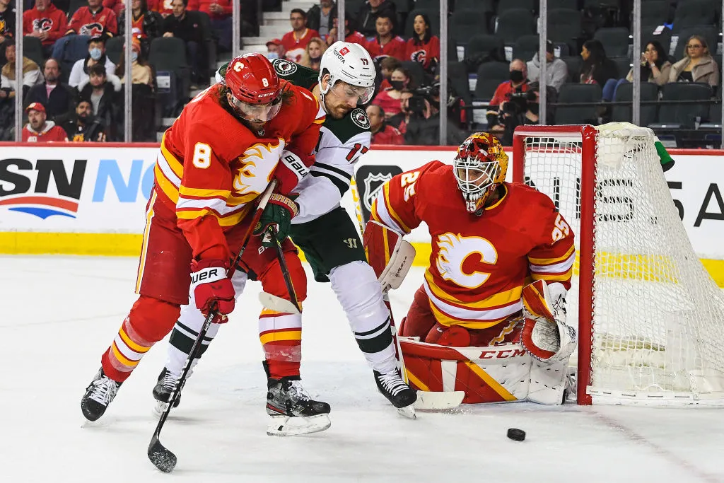 CALGARY, AB - FEBRUARY 26: Christopher Tanev #8 (L) and Jacob Markstrom #25 (R) of the Calgary Flames defend the net against Marcus Foligno #17 of the Minnesota Wild during an NHL game at Scotiabank Saddledome on February 26, 2022 in Calgary, Alberta, Canada. (Photo by Derek Leung/Getty Images)