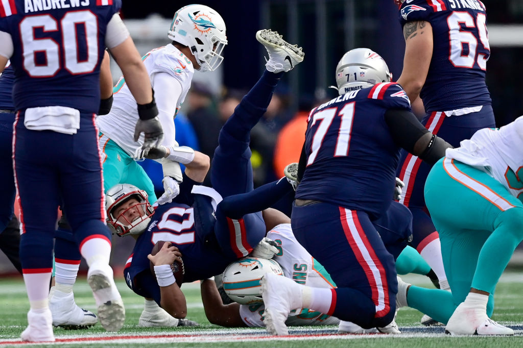FOXBOROUGH, MASSACHUSETTS - JANUARY 01: Mac Jones #10 of the New England Patriots is sacked by Christian Wilkins #94 of the Miami Dolphins during the second quarter at Gillette Stadium on January 01, 2023 in Foxborough, Massachusetts. (Photo by Billie Weiss/Getty Images)
