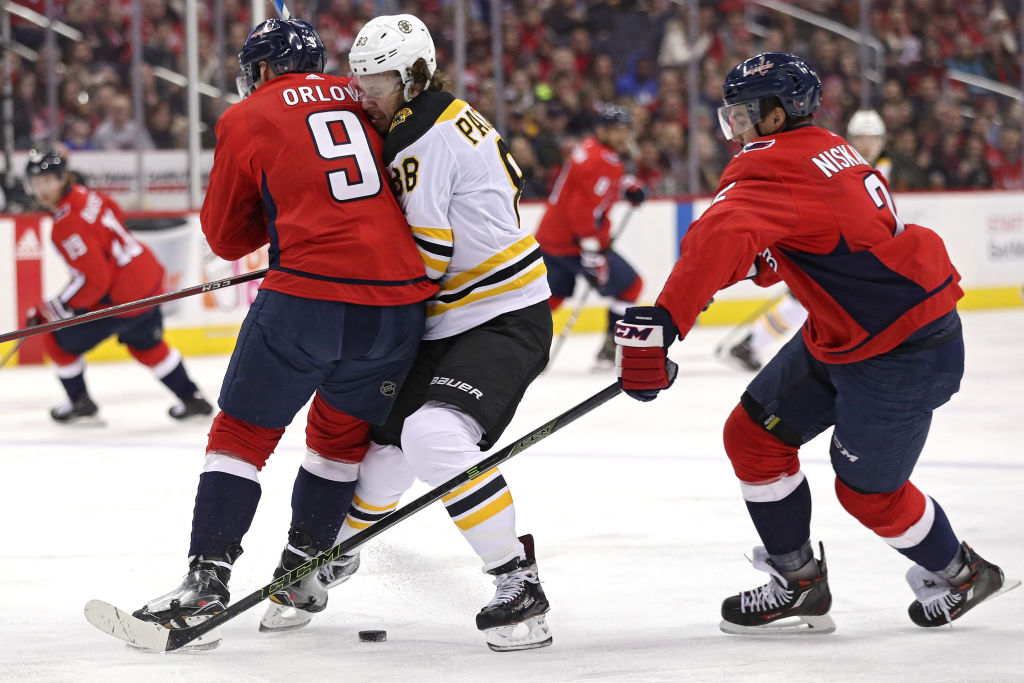 WASHINGTON, DC - DECEMBER 28: David Pastrnak #88 of the Boston Bruins is checked by Dmitry Orlov #9 of the Washington Capitals during the first period at Capital One Arena on December 28, 2017 in Washington, DC. (Photo by Patrick Smith/Getty Images)