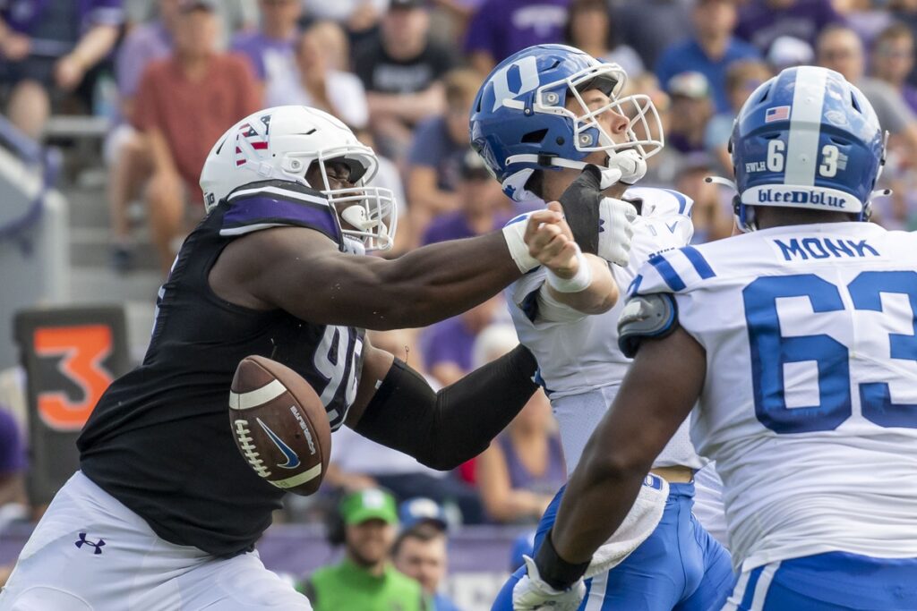 Sep 10, 2022; Evanston, Illinois, USA; Northwestern Wildcats defensive lineman Adetomiwa Adebawore (99) forces a fumble on Duke Blue Devils quarterback Riley Leonard (13) during the second quarter at Ryan Field. Credit: Patrick Gorski-USA TODAY Sports