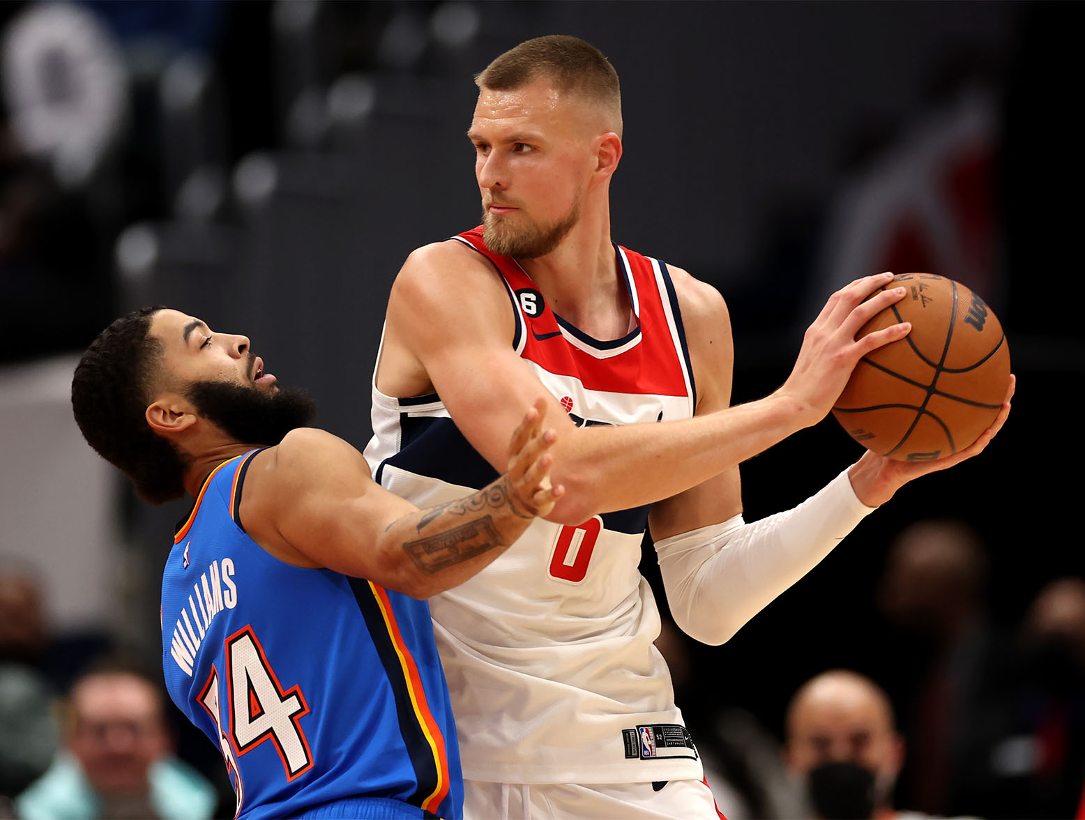 WASHINGTON, DC - NOVEMBER 16: Kristaps Porzingis #6 of the Washington Wizards looks to pass around Kenrich Williams #34 of the Oklahoma City Thunder in the first half at Capital One Arena on November 16, 2022 in Washington, DC. NOTE TO USER: User expressly acknowledges and agrees that, by downloading and or using this photograph, User is consenting to the terms and conditions of the Getty Images License Agreement. (Photo by Rob Carr/Getty Images)