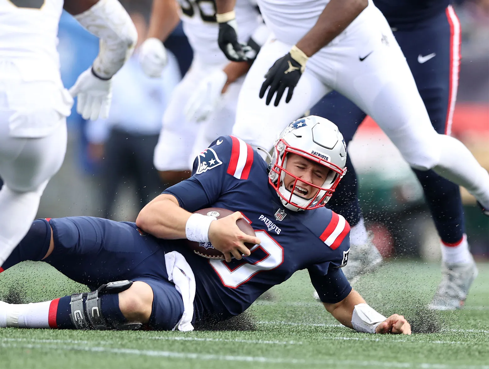 FOXBOROUGH, MASSACHUSETTS - SEPTEMBER 26: Quarterback Mac Jones #10 of the New England Patriots slides on the turf during the game against the New Orleans Saints at Gillette Stadium on September 26, 2021 in Foxborough, Massachusetts. (Photo by Elsa/Getty Images)