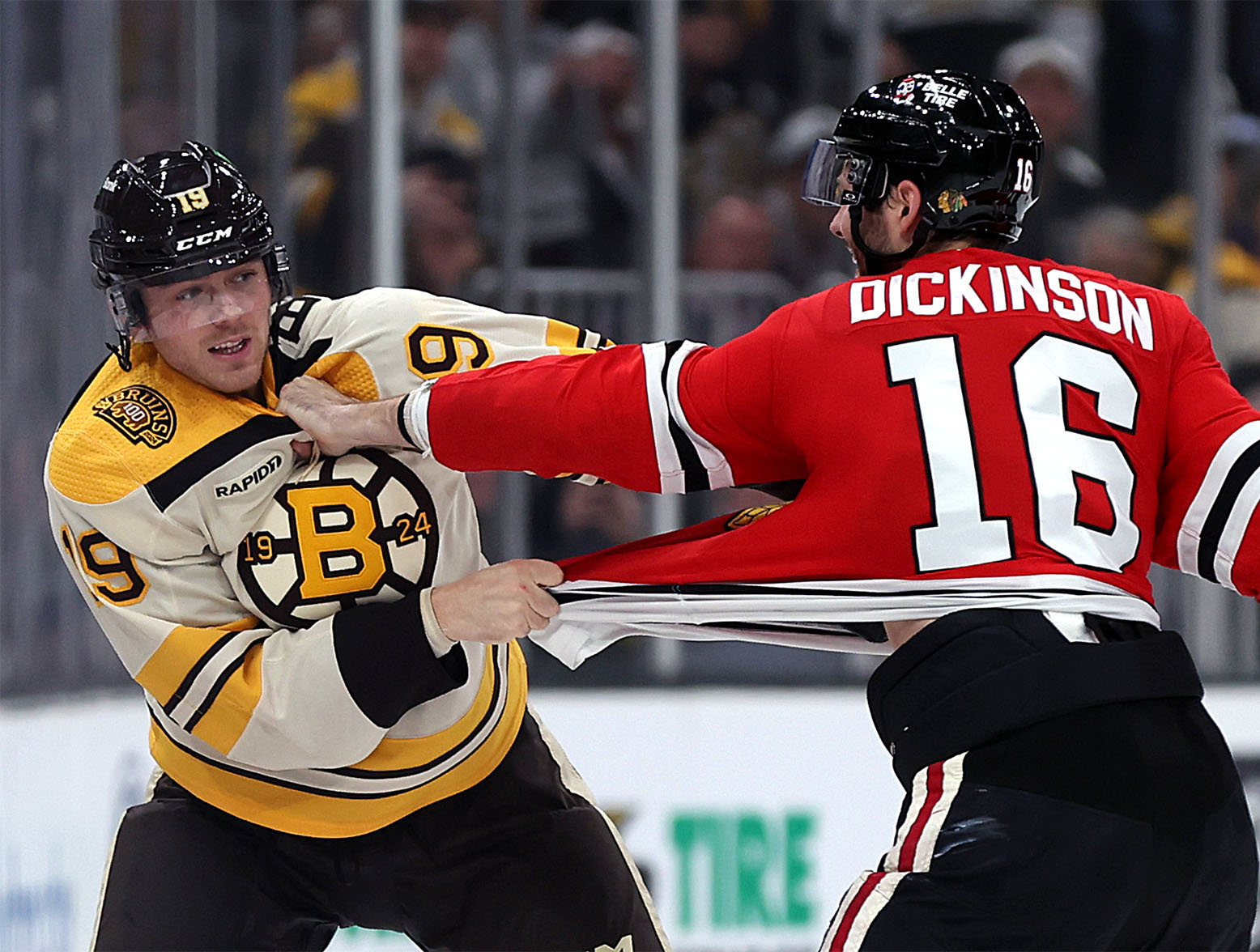 BOSTON, MASSACHUSETTS - OCTOBER 11: Johnny Beecher #19 of the Boston Bruins fights with Jason Dickinson #16 of the Chicago Blackhawks during the third period of the Bruins home opener at TD Garden on October 11, 2023 in Boston, Massachusetts. The Bruins defeat the Blackhawks 3-1. (Photo by Maddie Meyer/Getty Images)