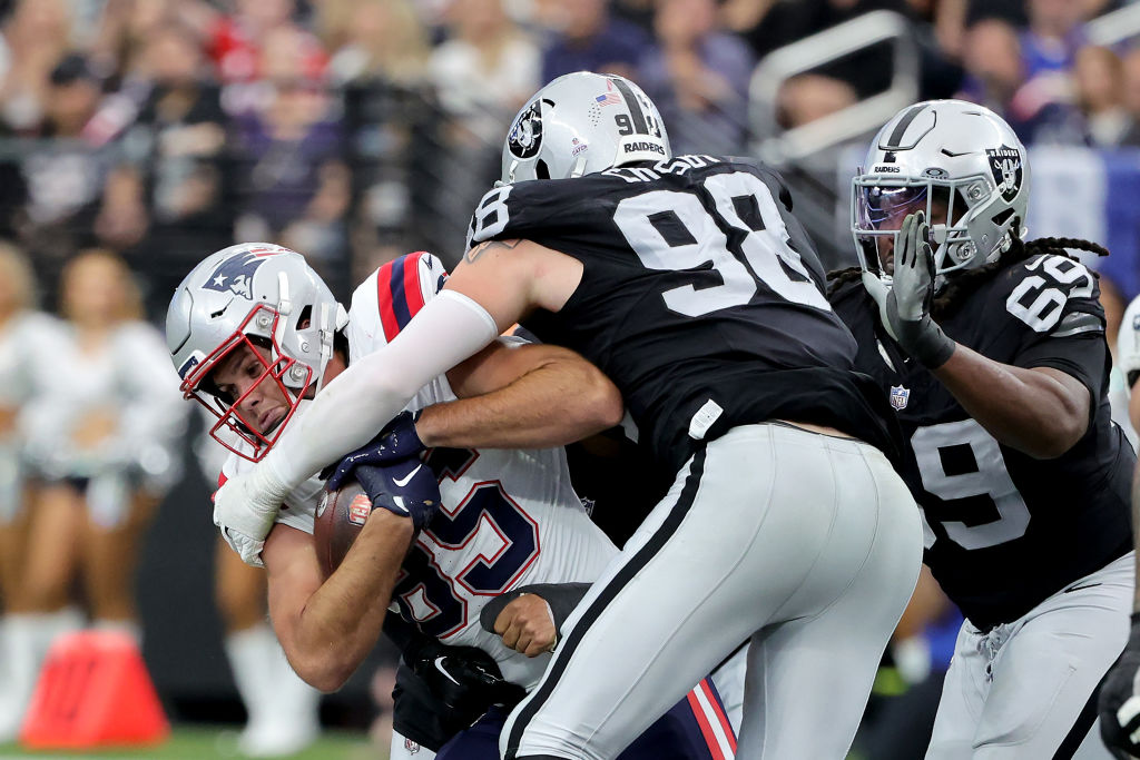 LAS VEGAS, NEVADA - OCTOBER 15: Maxx Crosby #98 of the Las Vegas Raiders and Adam Butler #69 of the Las Vegas Raiders tackle Hunter Henry #85 of the New England Patriots during the second quarter at Allegiant Stadium on October 15, 2023 in Las Vegas, Nevada. (Photo by Ethan Miller/Getty Images)