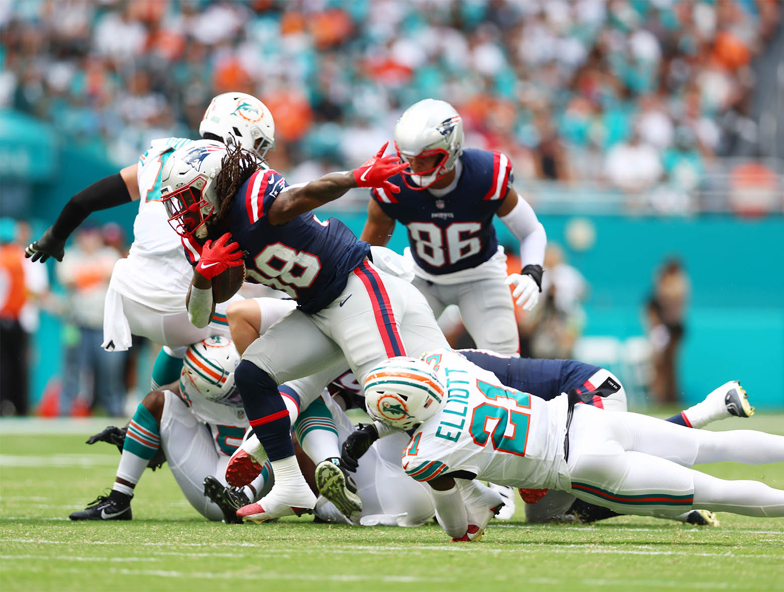 MIAMI GARDENS, FLORIDA - OCTOBER 29: DeShon Elliott #21 of the Miami Dolphins attempts to tackle Rhamondre Stevenson #38 of the New England Patriots during the first quarter at Hard Rock Stadium on October 29, 2023 in Miami Gardens, Florida. (Photo by Megan Briggs/Getty Images)