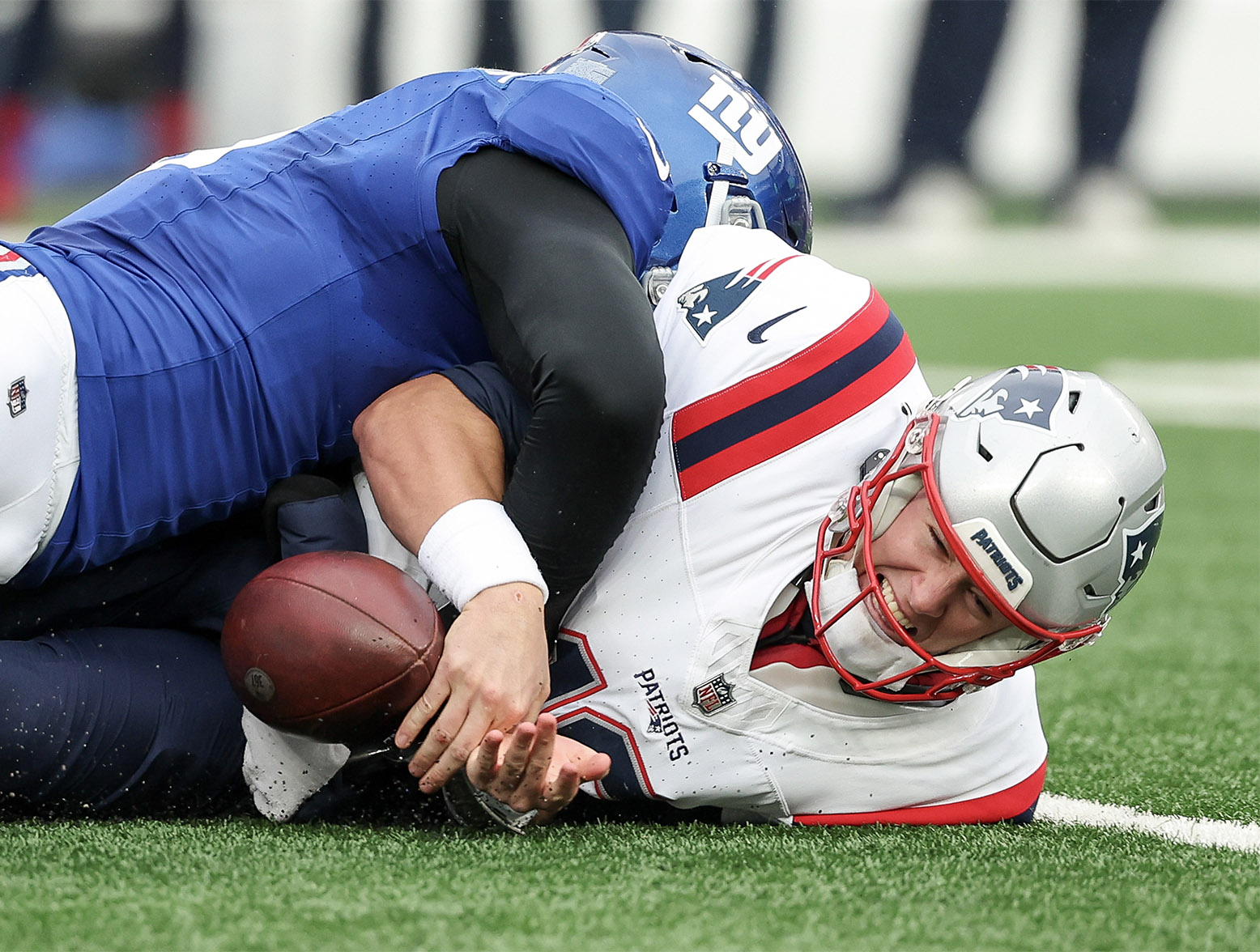 EAST RUTHERFORD, NEW JERSEY - NOVEMBER 26: Mac Jones #10 of the New England Patriots fumbles the ball while being tackled by Kayvon Thibodeaux #5 of the New York Giants during the second quarter at MetLife Stadium on November 26, 2023 in East Rutherford, New Jersey. (Photo by Al Bello/Getty Images)