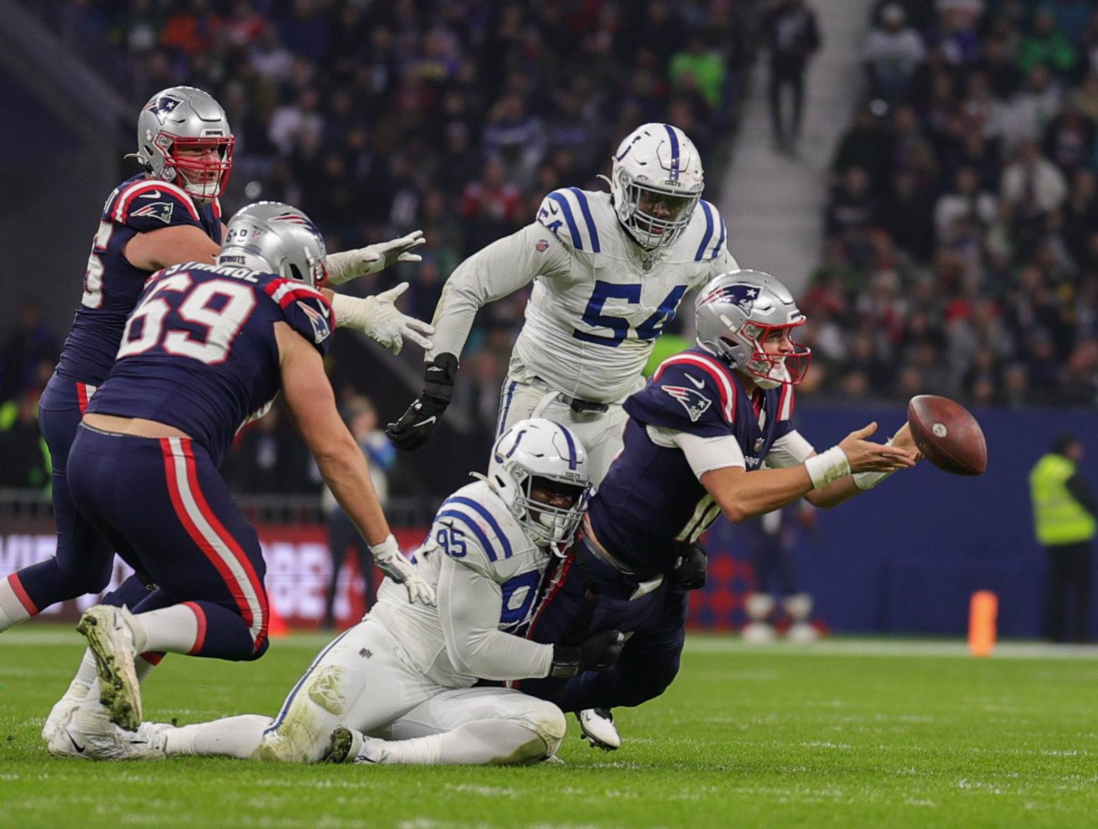 Nov 12, 2023; Frankfurt, Germany; New England Patriots quarterback Mac Jones (10) attempts to pass the ball under pressure by Indianapolis Colts defensive end Adetomiwa Adebawore (95) in the third quarter during an International Series game at Deutsche Bank Park. Credit: Nathan Ray Seebeck-USA TODAY Sports