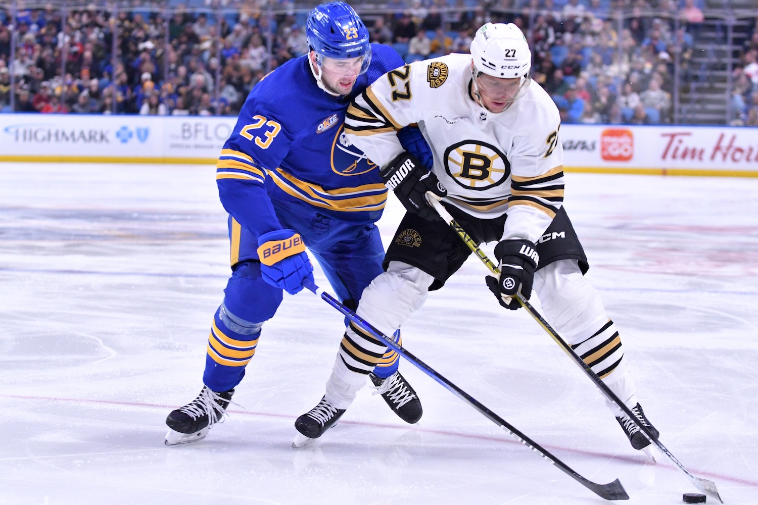 Nov 14, 2023; Buffalo, New York, USA; Boston Bruins defenseman Hampus Lindholm (27) and Buffalo Sabres defenseman Mattias Samuelsson (23) battle for the puck in the first period at KeyBank Center. Mandatory Credit: Mark Konezny-USA TODAY Sports