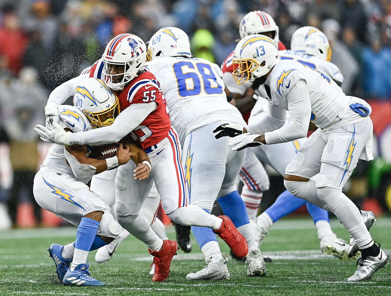FOXBOROUGH, MASSACHUSETTS - DECEMBER 03: Austin Ekeler #30 of the Los Angeles Chargers runs with the ball while being tackled by Josh Uche #55 of the New England Patriots in the second quarter at Gillette Stadium on December 03, 2023 in Foxborough, Massachusetts. (Photo by Billie Weiss/Getty Images)