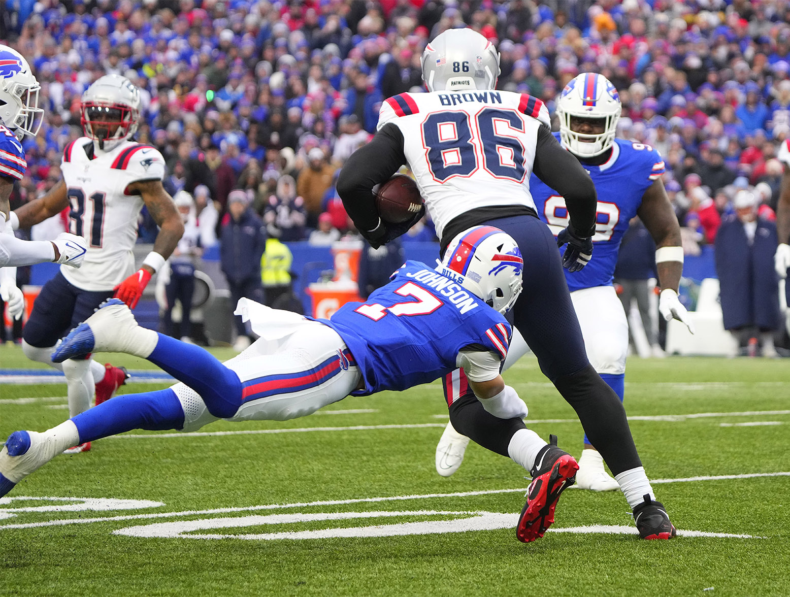 Dec 31, 2023; Orchard Park, New York, USA; New England Patriots tight end Pharaoh Brown (86) runs with the ball after making a catch and is tackled by Buffalo Bills cornerback Taron Johnson (7) during the first half at Highmark Stadium. Mandatory Credit: Gregory Fisher-USA TODAY Sports