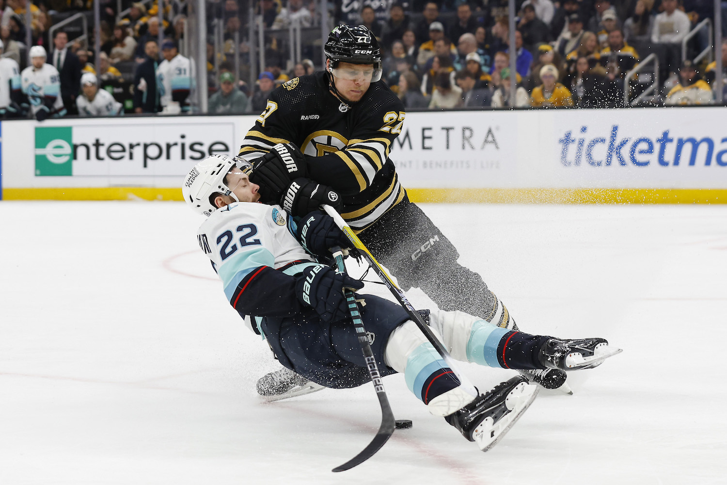 BOSTON, MA - FEBRUARY 15: Hampus Lindholm #27 of the Boston Bruins checks Oliver Bjorkstrand #22 of the Seattle Kraken off the puck during the second period at TD Garden on February 15, 2024 in Boston, Massachusetts. (Photo By Winslow Townson/Getty Images)