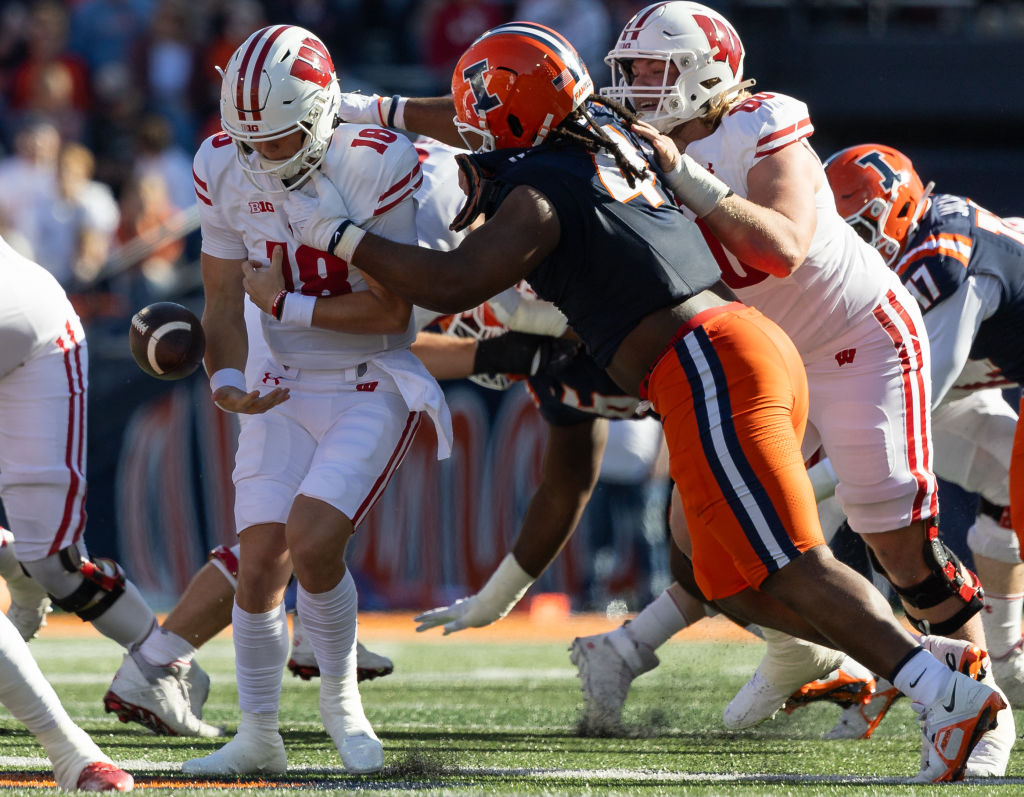 CHAMPAIGN, ILLINOIS - OCTOBER 21: Braedyn Locke #18 of the Wisconsin Badgers fumbles the ball as Jer'Zhan Newton #4 of the Illinois Fighting Illini makes the hit during the first half at Memorial Stadium on October 21, 2023 in Champaign, Illinois. (Photo by Michael Hickey/Getty Images)