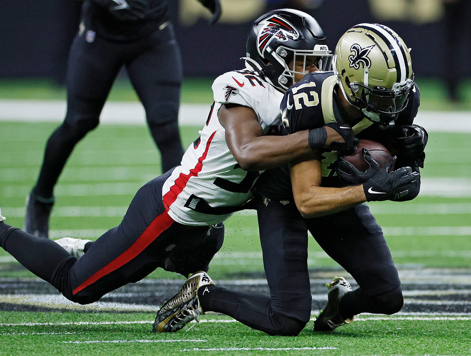 NEW ORLEANS, LOUISIANA - DECEMBER 18: Chris Olave #12 of the New Orleans Saints is tackled by Jaylinn Hawkins #32 of the Atlanta Falcons during the first half at Caesars Superdome on December 18, 2022 in New Orleans, Louisiana. (Photo by Chris Graythen/Getty Images)