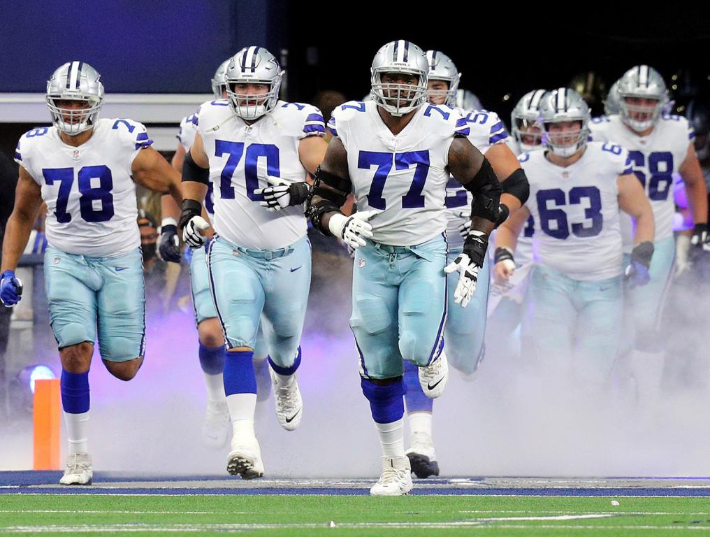 ARLINGTON, TEXAS - OCTOBER 03: Terence Steele #78, Zack Martin #70, and Tyron Smith #77 of the Dallas Cowboys lead the team on to the field before the game against the Carolina Panthers at AT&T Stadium on October 03, 2021 in Arlington, Texas. (Photo by Richard Rodriguez/Getty Images)