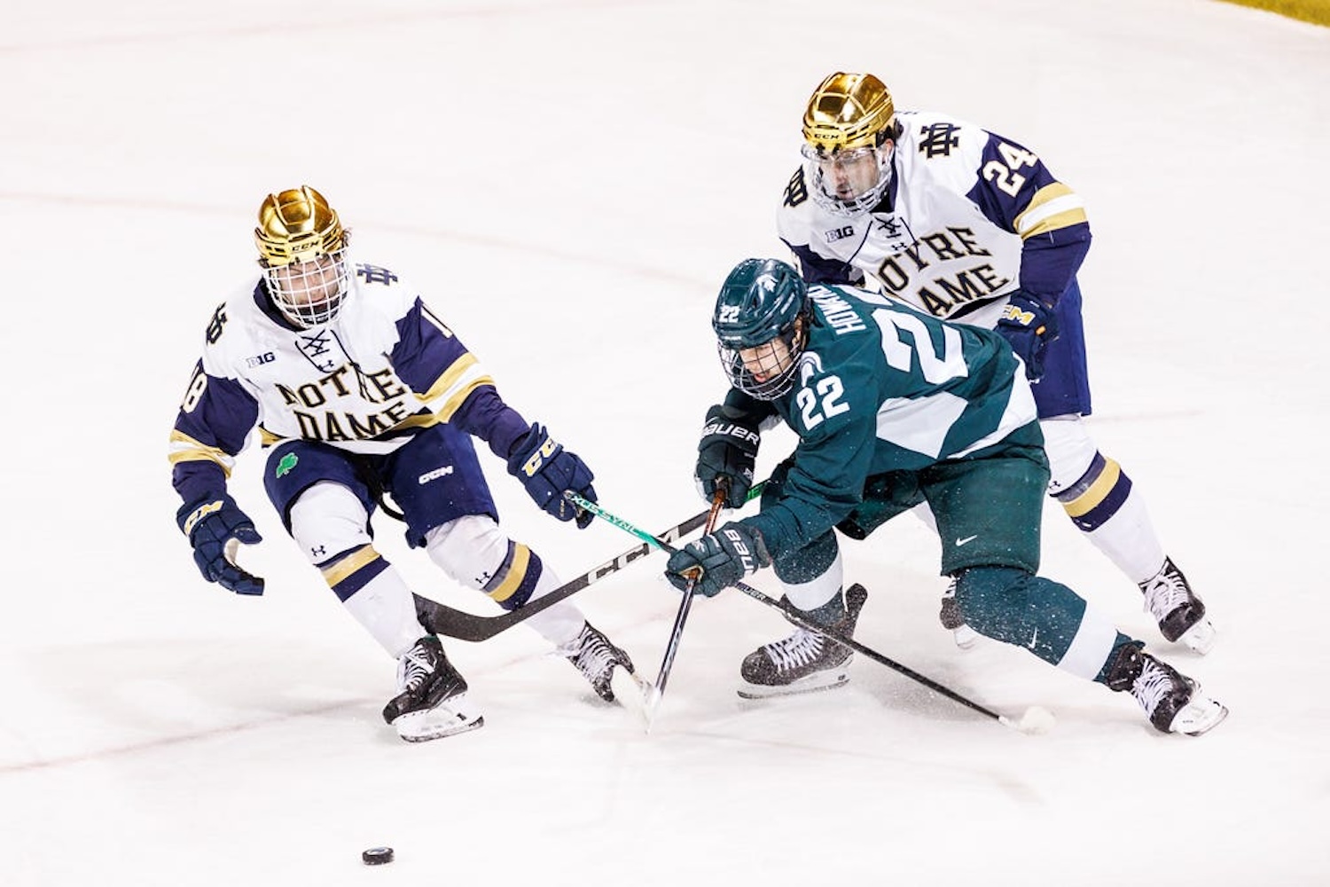 Michigan State forward Isaac Howard (22), Notre Dame forward Patrick Moynihan (18), and Notre Dame defenseman Drew Bavaro (24) battle for the puck during the Michigan State-Notre Dame NCAA hockey game on Friday, February 02, 2024, at Compton Family Ice Arena in South Bend, Indiana.