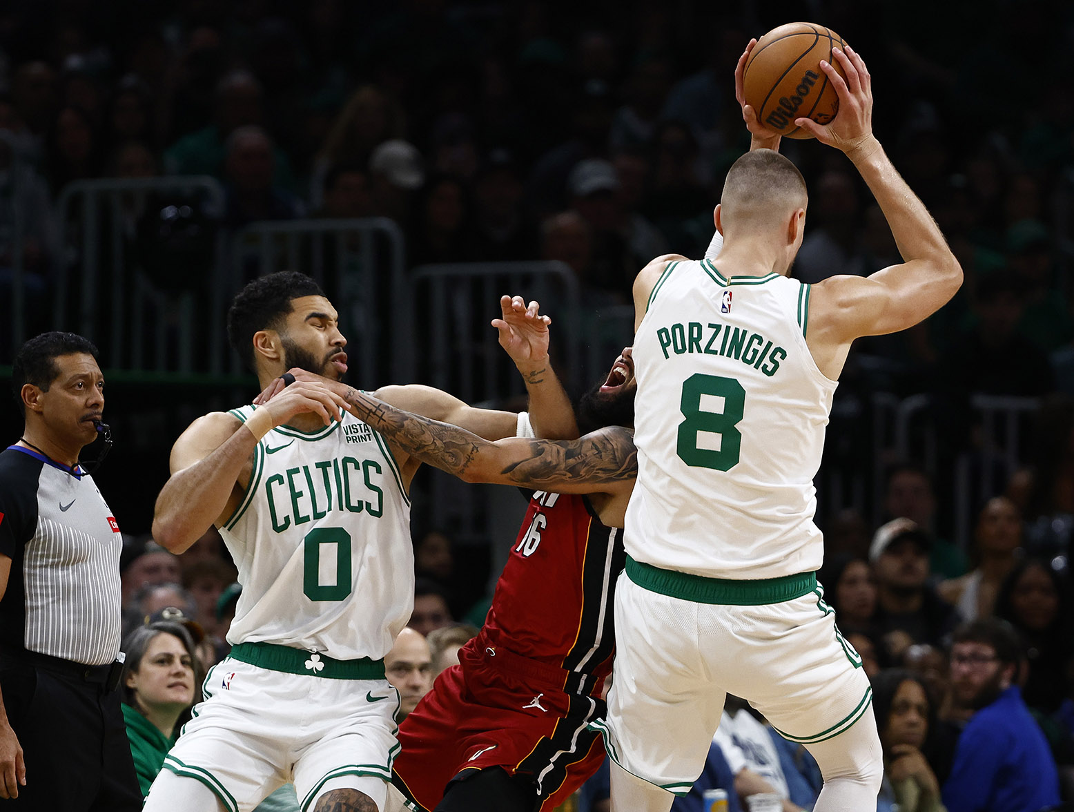 BOSTON, MA - APRIL 21: Caleb Martin #16 of the Miami Heat runs into Kristaps Porzingis #8 of the Boston Celtics as he tries to keep Jayson Tatum #0 from the ball during the first quarter of game one of the Eastern Conference First Round Playoffs at TD Garden on April 21, 2024 in Boston, Massachusetts. (Photo By Winslow Townson/Getty Images)