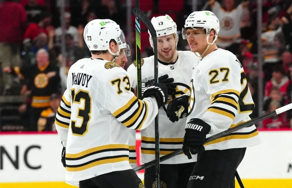 Apr 4, 2024; Raleigh, North Carolina, USA; Boston Bruins defenseman Hampus Lindholm (27) is congratulated by defenseman Charlie McAvoy (73) center Charlie Coyle (13) and left wing Brad Marchand (63) after his empty net goal against the Carolina Hurricanes during the third period at PNC Arena. Mandatory Credit: James Guillory-USA TODAY Sports