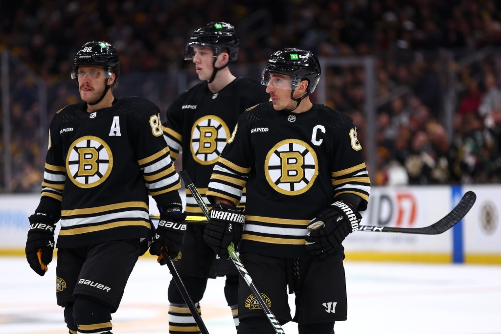 BOSTON, MASSACHUSETTS - NOVEMBER 09: David Pastrnak #88, Mason Lohrei #6, and Brad Marchand #63 of the Boston Bruins look on during the first period against the New York Islanders at TD Garden on November 09, 2023 in Boston, Massachusetts. (Photo by Maddie Meyer/Getty Images)