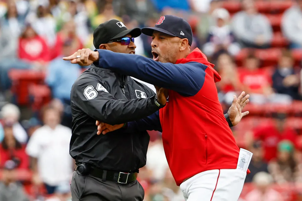 BOSTON, MA - SEPTEMBER 22: Manager Alex Cora #13 of the Boston Red Sox is held back by umpire Alan Porter #64 after he got thrown out of the game for arguing after the umpires ruled a Red Sox infielder had blocked the base trying to tag a Minnesota Twins runner out during the first inning of game one of a doubleheader at Fenway Park on September 22, 2024 in Boston, Massachusetts. (Photo By Winslow Townson/Getty Images)