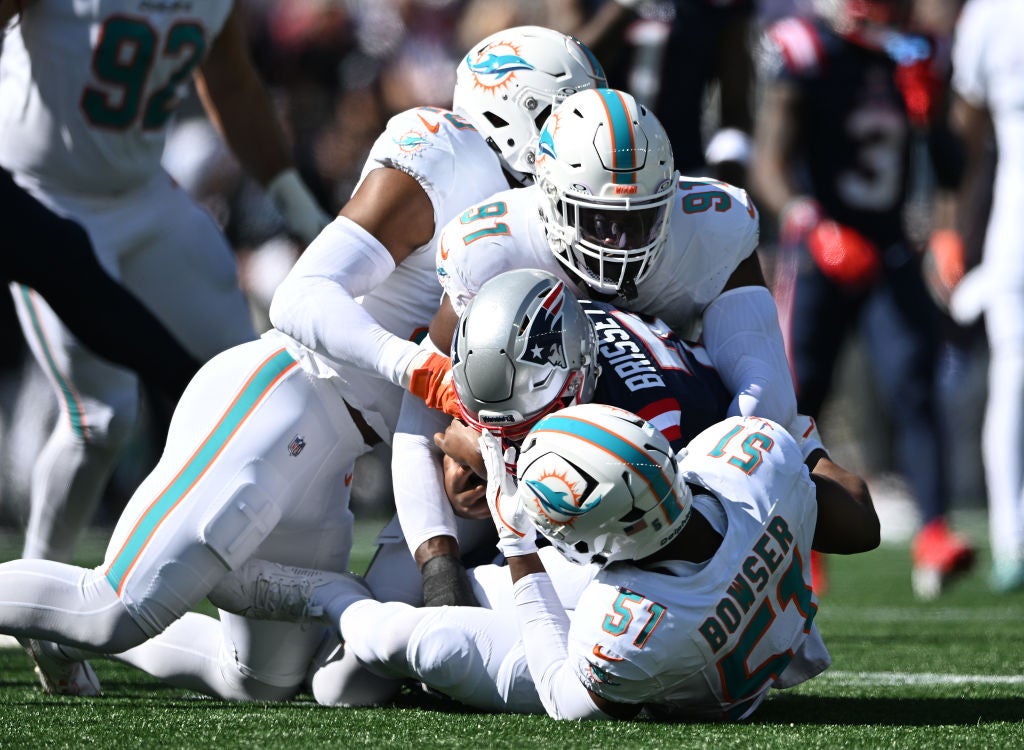 FOXBOROUGH, MASSACHUSETTS - OCTOBER 06: Tyus Bowser #51 and Da'Shawn Hand #91 of the Miami Dolphins tackle Jacoby Brissett #7 of the New England Patriots during the first half at Gillette Stadium on October 06, 2024 in Foxborough, Massachusetts. (Photo by Jaiden Tripi/Getty Images)