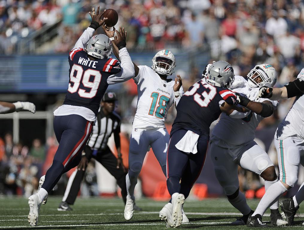 FOXBOROUGH, MASSACHUSETTS - OCTOBER 06: Tyler Huntley #18 of the Miami Dolphins passes under pressure from Keion White #99 of the New England Patriots during the third quarter at Gillette Stadium on October 06, 2024 in Foxborough, Massachusetts. (Photo by Adam Hunger/Getty Images)