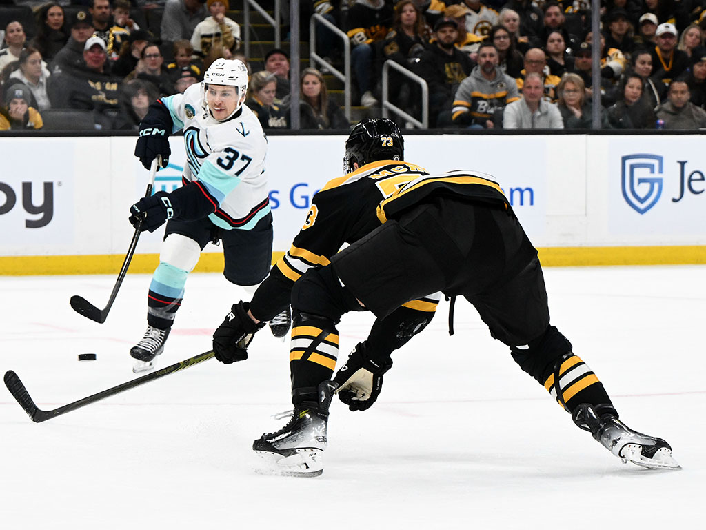 Nov 3, 2024; Boston, Massachusetts, USA; Seattle Kraken center Yanni Gourde (37) takes a shot in front of Boston Bruins defenseman Charlie McAvoy (73)  during the second period at the TD Garden. Mandatory Credit: Brian Fluharty-Imagn Images