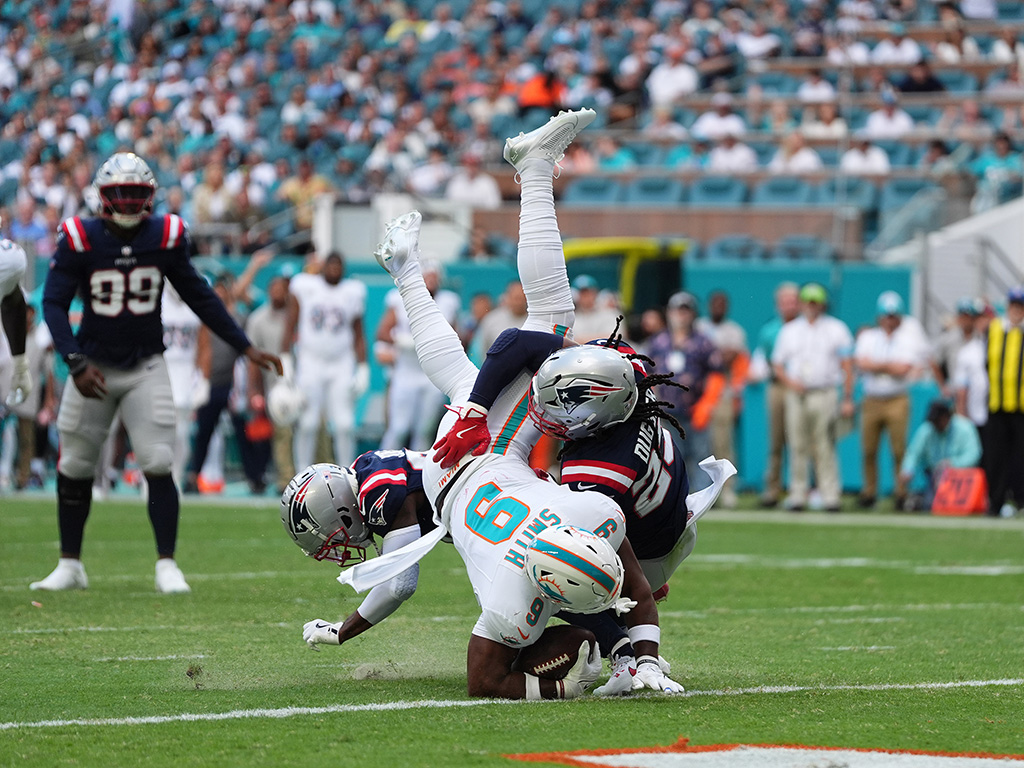 Nov 24, 2024; Miami Gardens, Florida, USA; Miami Dolphins tight end Jonnu Smith (9) is upended on the goal line for a touchdown by New England Patriots safety Kyle Dugger (23) during the first half at Hard Rock Stadium. Mandatory Credit: Jasen Vinlove-Imagn Images