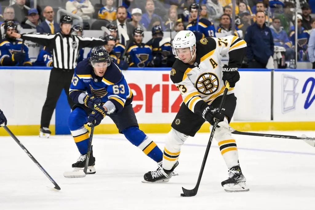 Nov 12, 2024; St. Louis, Missouri, USA;  Boston Bruins defenseman Charlie McAvoy (73) controls the puck as St. Louis Blues left wing Jake Neighbours (63) defends during the third period at Enterprise Center. Mandatory Credit: Jeff Curry-Imagn Images