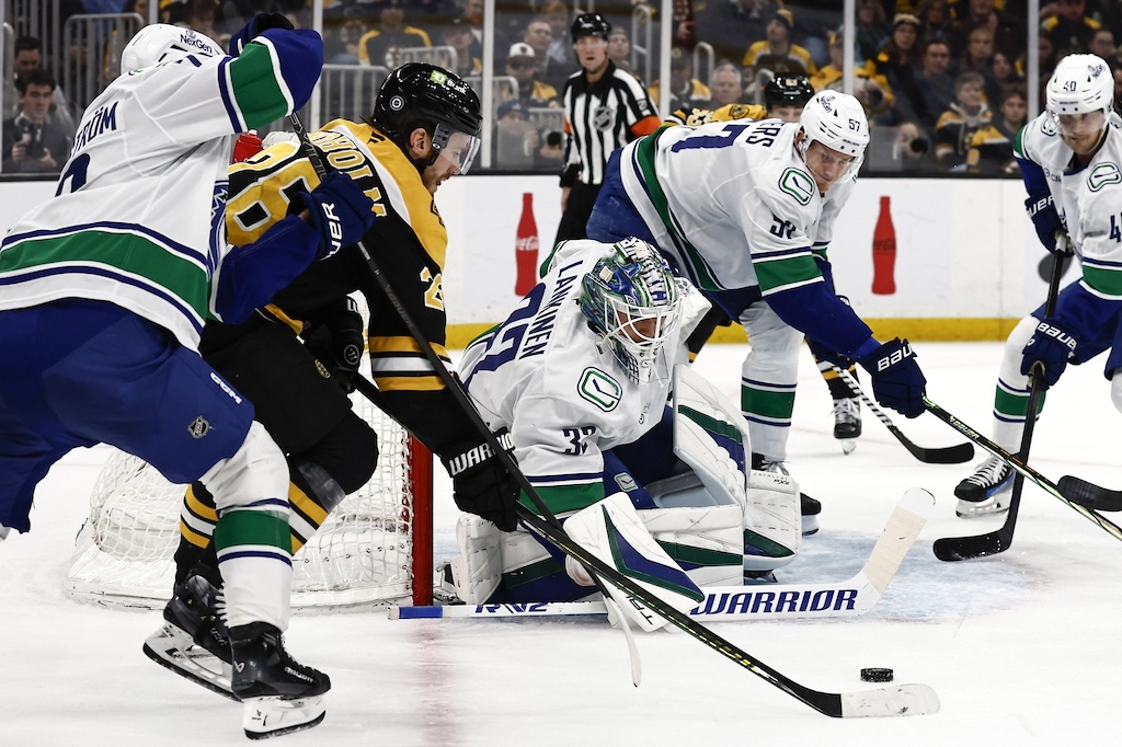 Nov 26, 2024; Boston, Massachusetts, USA; Boston Bruins center Elias Lindholm (28) tries to get to a loose puck next to Vancouver Canucks goaltender Kevin Lankinen (32) during the first period at TD Garden. Mandatory Credit: Winslow Townson-Imagn Images